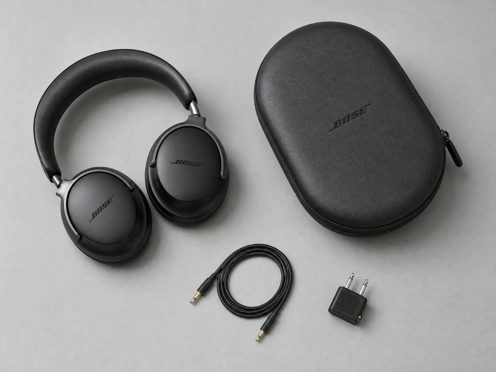 Black over-ear headphones, their case, and cable arranged in a clean top-down composition.