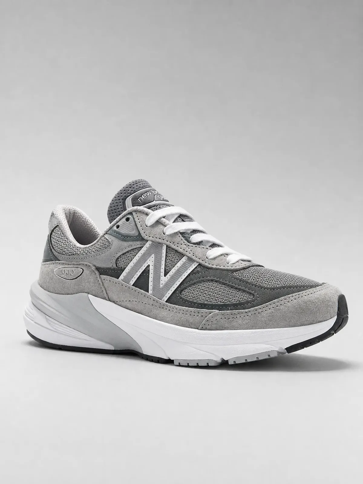 A gray performance shoe photographed to keep mesh, suede overlays, seams, and layered midsole construction readable.